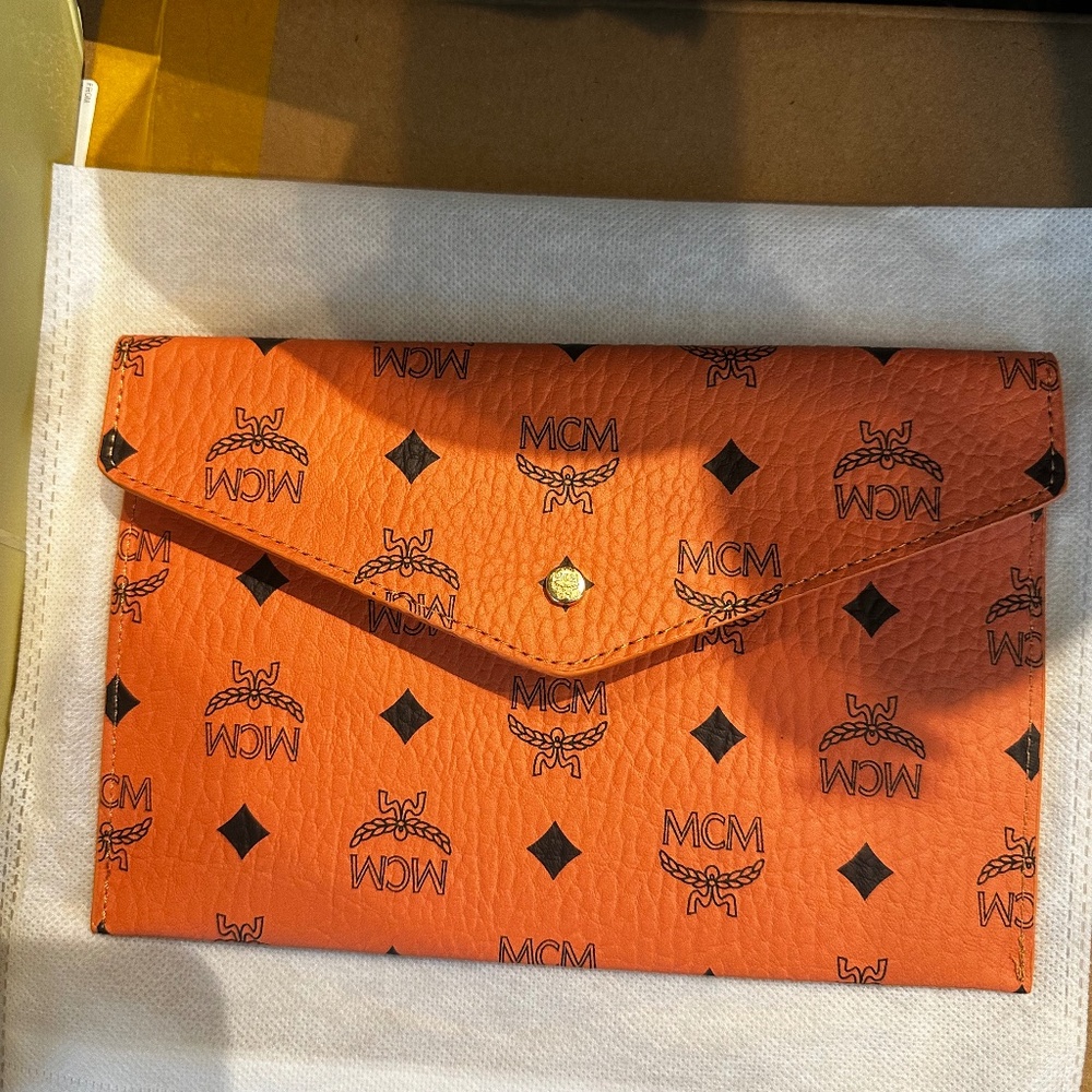 Elegant cognac clutch with iconic MCM logo. Sleek and versatile design